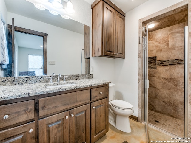 bathroom featuring toilet, a shower with door, tile flooring, and vanity