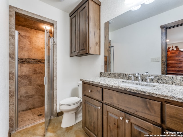 bathroom featuring toilet, a shower with shower door, and large vanity