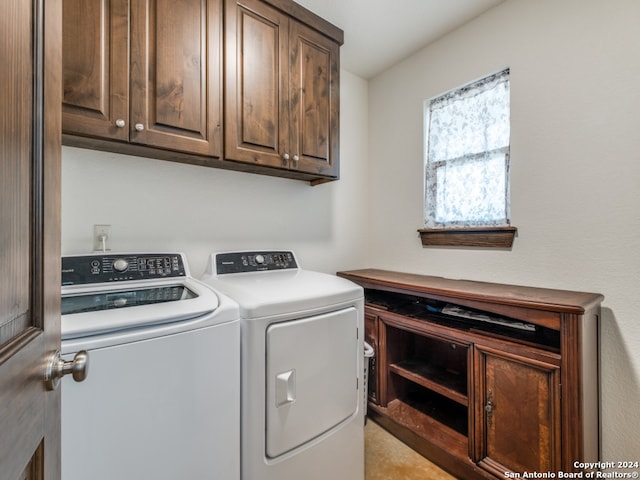 washroom with washing machine and clothes dryer and cabinets