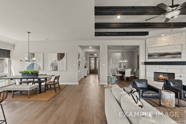 living room featuring beam ceiling, dark hardwood / wood-style flooring, ceiling fan with notable chandelier, and a fireplace