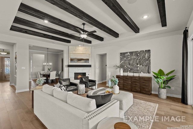 living room featuring beam ceiling, a fireplace, light hardwood / wood-style floors, and ceiling fan with notable chandelier