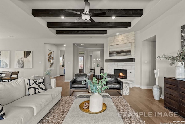 living room featuring a stone fireplace, dark hardwood / wood-style floors, beamed ceiling, and ceiling fan with notable chandelier