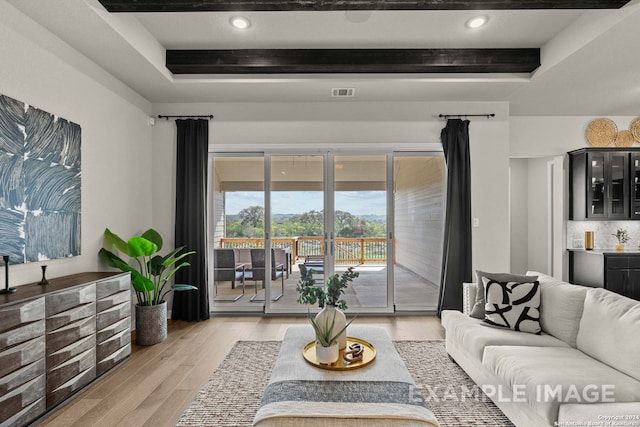 living room with a raised ceiling, light hardwood / wood-style floors, and beamed ceiling