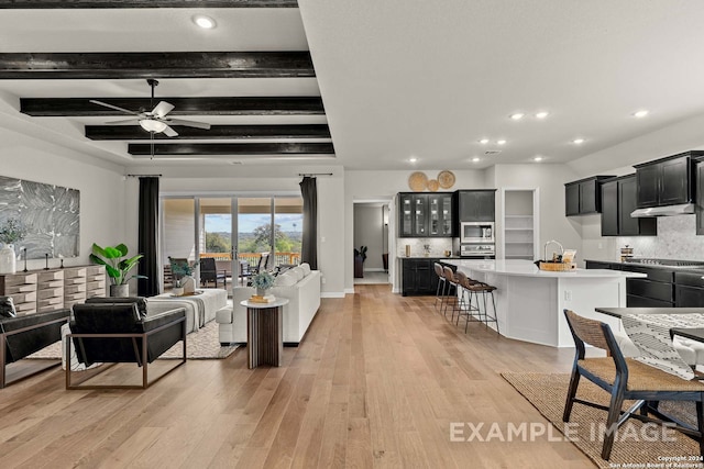 living room featuring light hardwood / wood-style floors, ceiling fan, and beamed ceiling