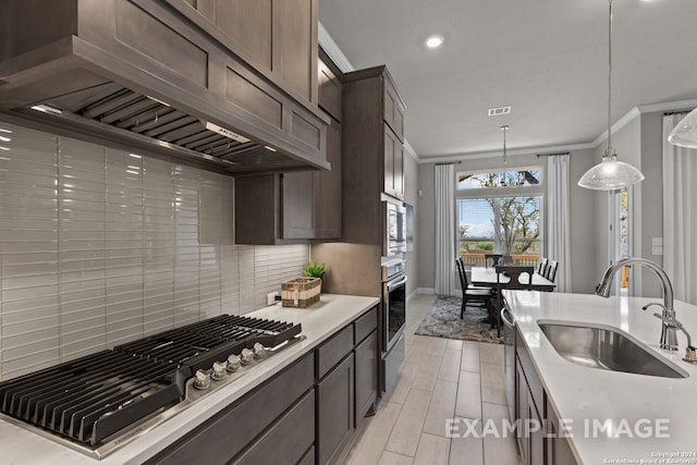 kitchen featuring stainless steel appliances, decorative light fixtures, custom exhaust hood, tasteful backsplash, and sink