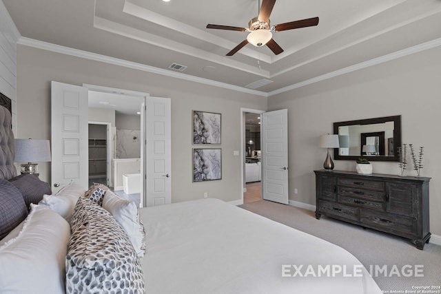 carpeted bedroom featuring a raised ceiling, ensuite bath, ceiling fan, and crown molding