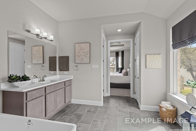 bathroom featuring lofted ceiling, vanity, a healthy amount of sunlight, and tile flooring