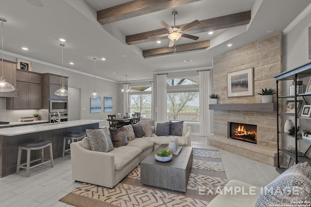 living room featuring crown molding, sink, ceiling fan, and a stone fireplace