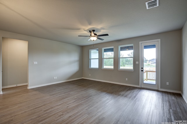 spare room with ceiling fan, dark wood-type flooring, and a healthy amount of sunlight