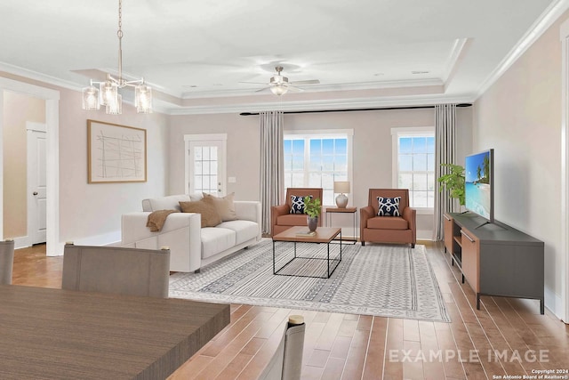 living room with crown molding, ceiling fan with notable chandelier, a raised ceiling, and hardwood / wood-style floors