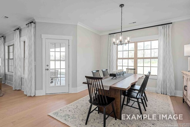 dining area featuring light wood-type flooring, ornamental molding, and a notable chandelier