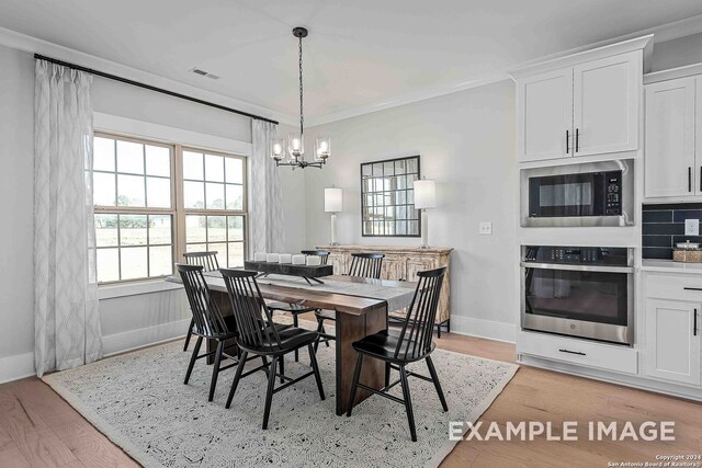 dining room with a chandelier, light hardwood / wood-style floors, and ornamental molding