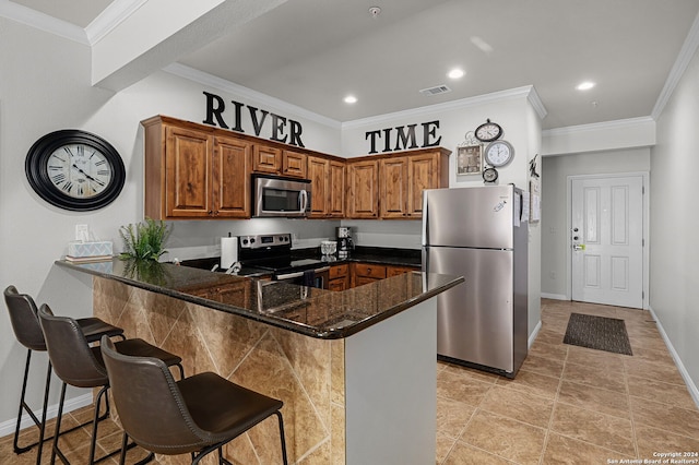 kitchen featuring appliances with stainless steel finishes, crown molding, dark stone counters, and kitchen peninsula