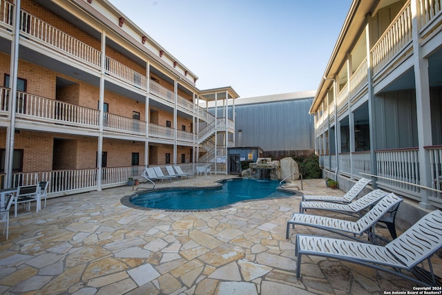 view of swimming pool with pool water feature and a patio area