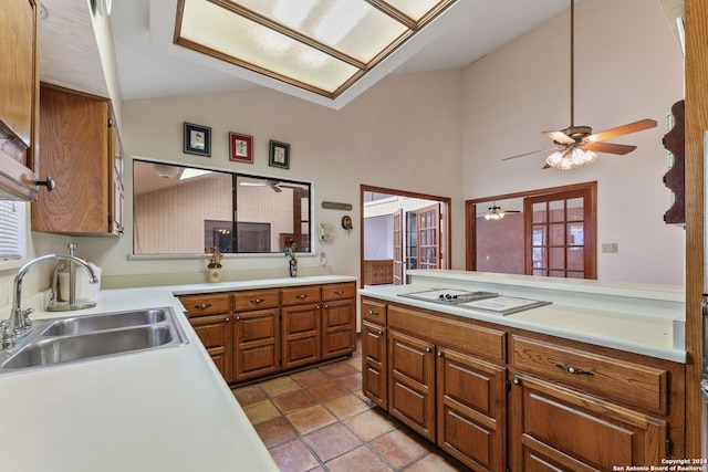 kitchen with ceiling fan, sink, white gas stovetop, high vaulted ceiling, and kitchen peninsula