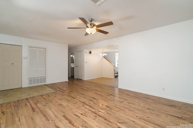 interior space with ceiling fan with notable chandelier and light hardwood / wood-style flooring