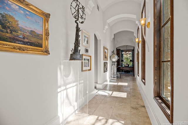 corridor with light tile patterned flooring and vaulted ceiling