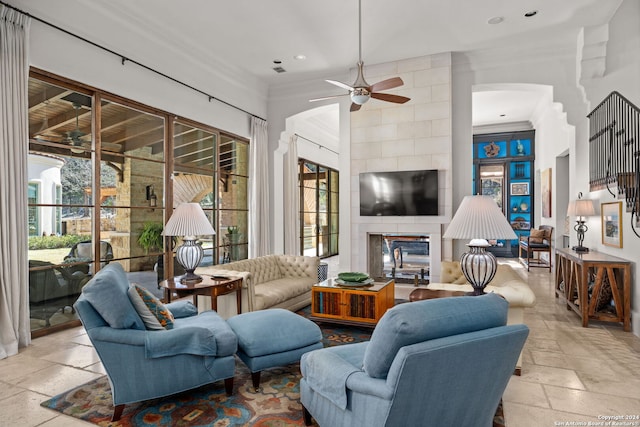 tiled living room with a tile fireplace, tile walls, a wealth of natural light, and ceiling fan