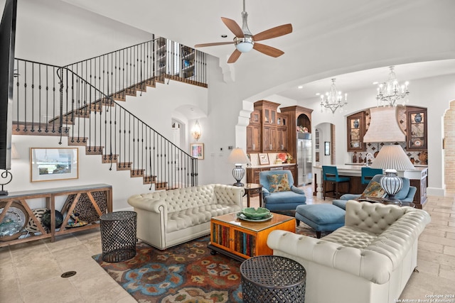 living room featuring light tile patterned flooring, ceiling fan with notable chandelier, and a towering ceiling