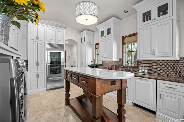 kitchen featuring light tile patterned floors, backsplash, washer and dryer, and stainless steel built in refrigerator