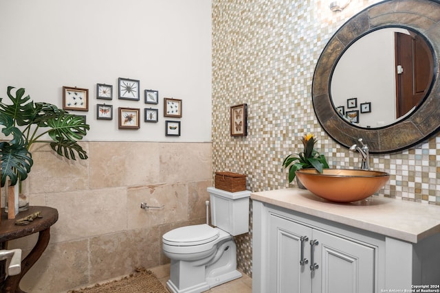 bathroom with tile walls, toilet, vanity, tile patterned flooring, and tasteful backsplash