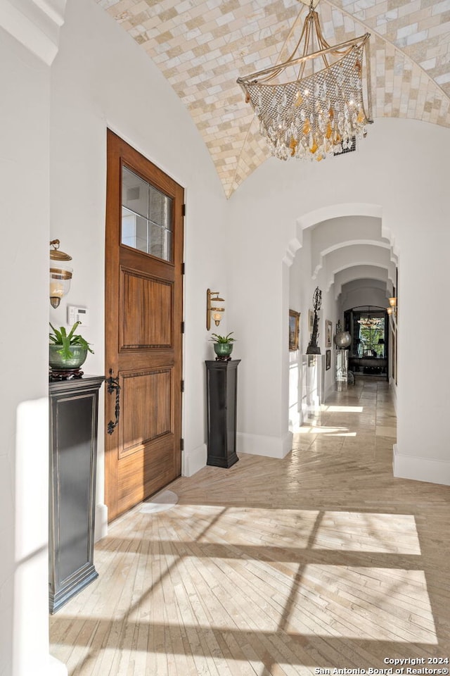 entryway featuring high vaulted ceiling, an inviting chandelier, and light hardwood / wood-style floors