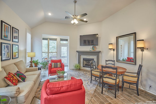 living room featuring lofted ceiling, a stone fireplace, hardwood / wood-style floors, and ceiling fan