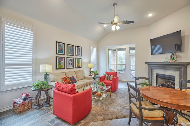 living room featuring ceiling fan, a fireplace, vaulted ceiling, and wood-type flooring