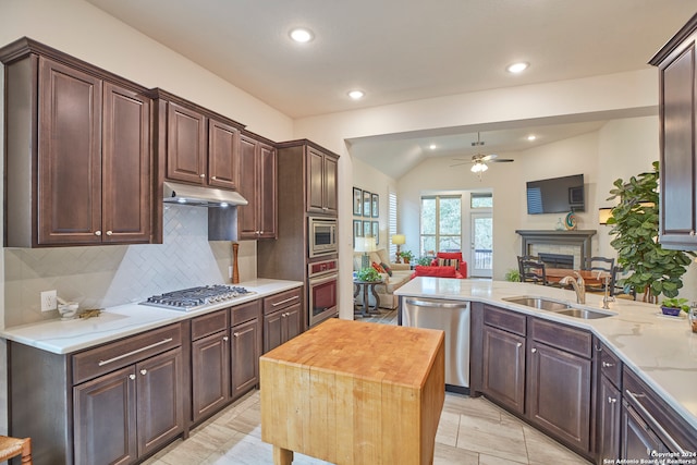 kitchen with stainless steel appliances, lofted ceiling, ceiling fan, wood counters, and sink