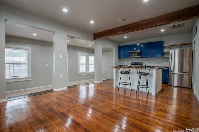 kitchen featuring dark hardwood / wood-style flooring, appliances with stainless steel finishes, a kitchen breakfast bar, and plenty of natural light