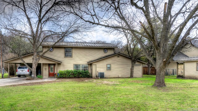 rear view of house featuring a lawn, a carport, and central AC unit