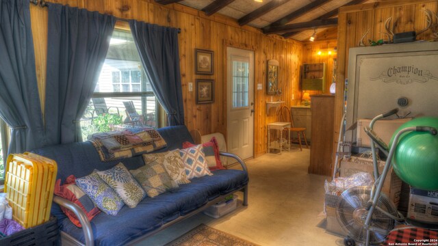 carpeted living room featuring plenty of natural light, wood walls, and vaulted ceiling with beams