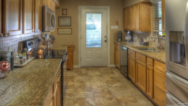 kitchen with sink, stainless steel appliances, light tile floors, light stone counters, and tasteful backsplash