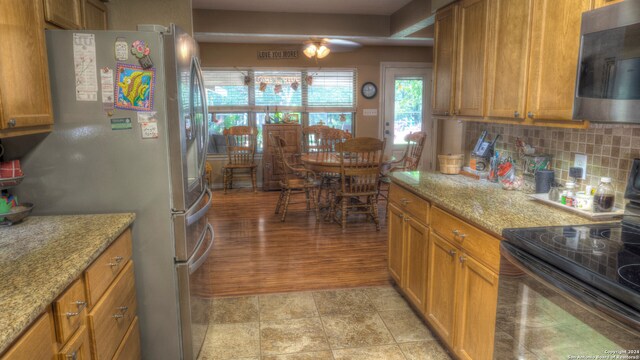 kitchen with light tile floors, light stone countertops, tasteful backsplash, and stainless steel appliances