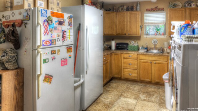 kitchen with white fridge, washer / dryer, light tile floors, and sink