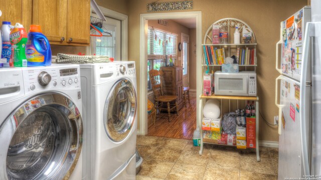 laundry area with washer and clothes dryer, cabinets, and light tile floors