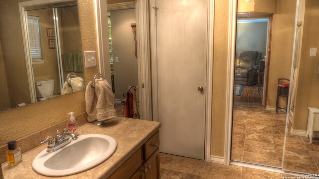 bathroom featuring toilet, large vanity, and tile flooring