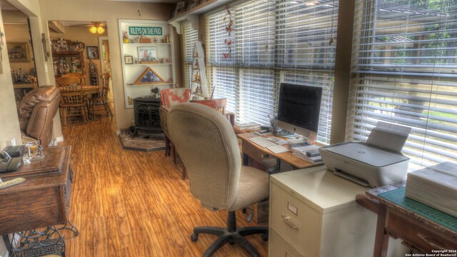 home office with light hardwood / wood-style floors and a wood stove