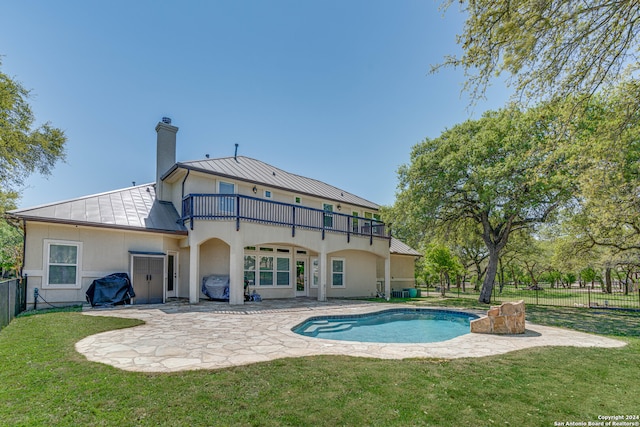 rear view of house featuring a yard, a balcony, a patio, and a fenced in pool