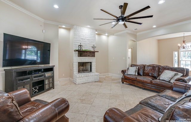 tiled living room featuring a fireplace, ceiling fan with notable chandelier, and crown molding