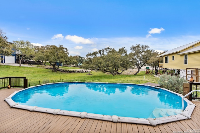 view of swimming pool with a deck and a lawn