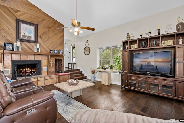 living room featuring a tiled fireplace, wooden walls, ceiling fan, and dark wood-type flooring