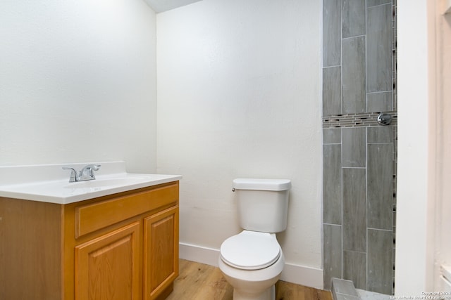 bathroom with toilet, vanity, hardwood / wood-style flooring, and tiled shower