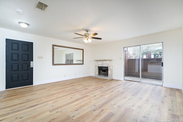 unfurnished living room featuring ceiling fan, a fireplace, and light wood-type flooring