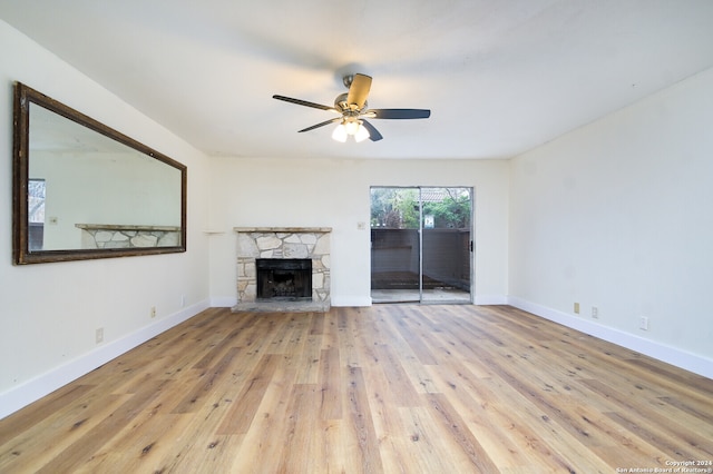 unfurnished living room featuring a stone fireplace, light hardwood / wood-style floors, and ceiling fan