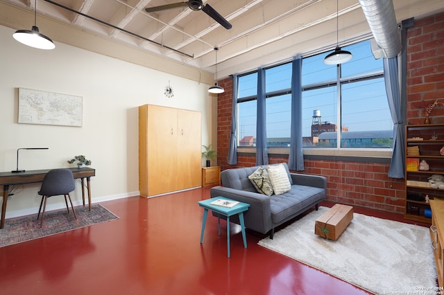 living room featuring ceiling fan, brick wall, concrete flooring, and a towering ceiling