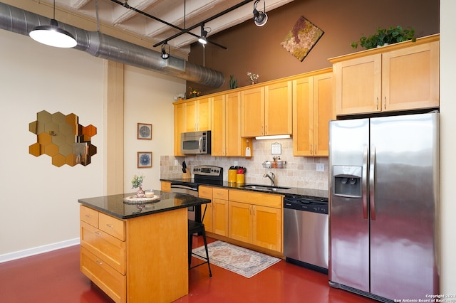 kitchen with backsplash, a kitchen breakfast bar, appliances with stainless steel finishes, sink, and a center island