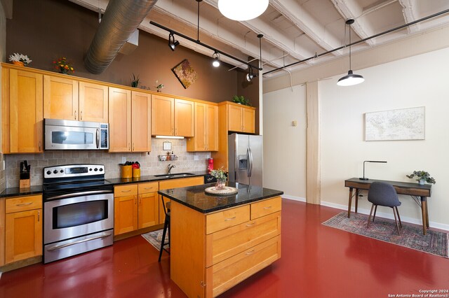 kitchen with sink, stainless steel appliances, backsplash, and a kitchen island