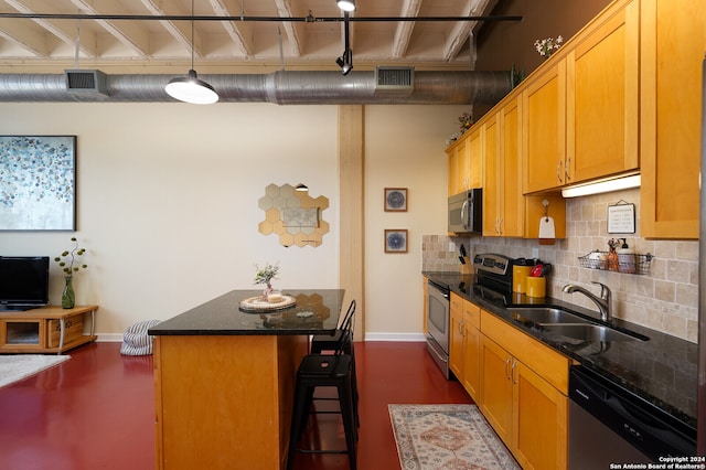 kitchen featuring appliances with stainless steel finishes, hanging light fixtures, tasteful backsplash, a kitchen bar, and sink