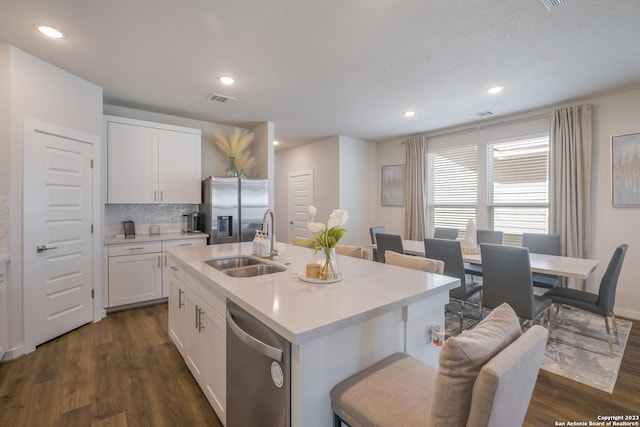 kitchen featuring sink, a kitchen island with sink, appliances with stainless steel finishes, and dark hardwood / wood-style flooring